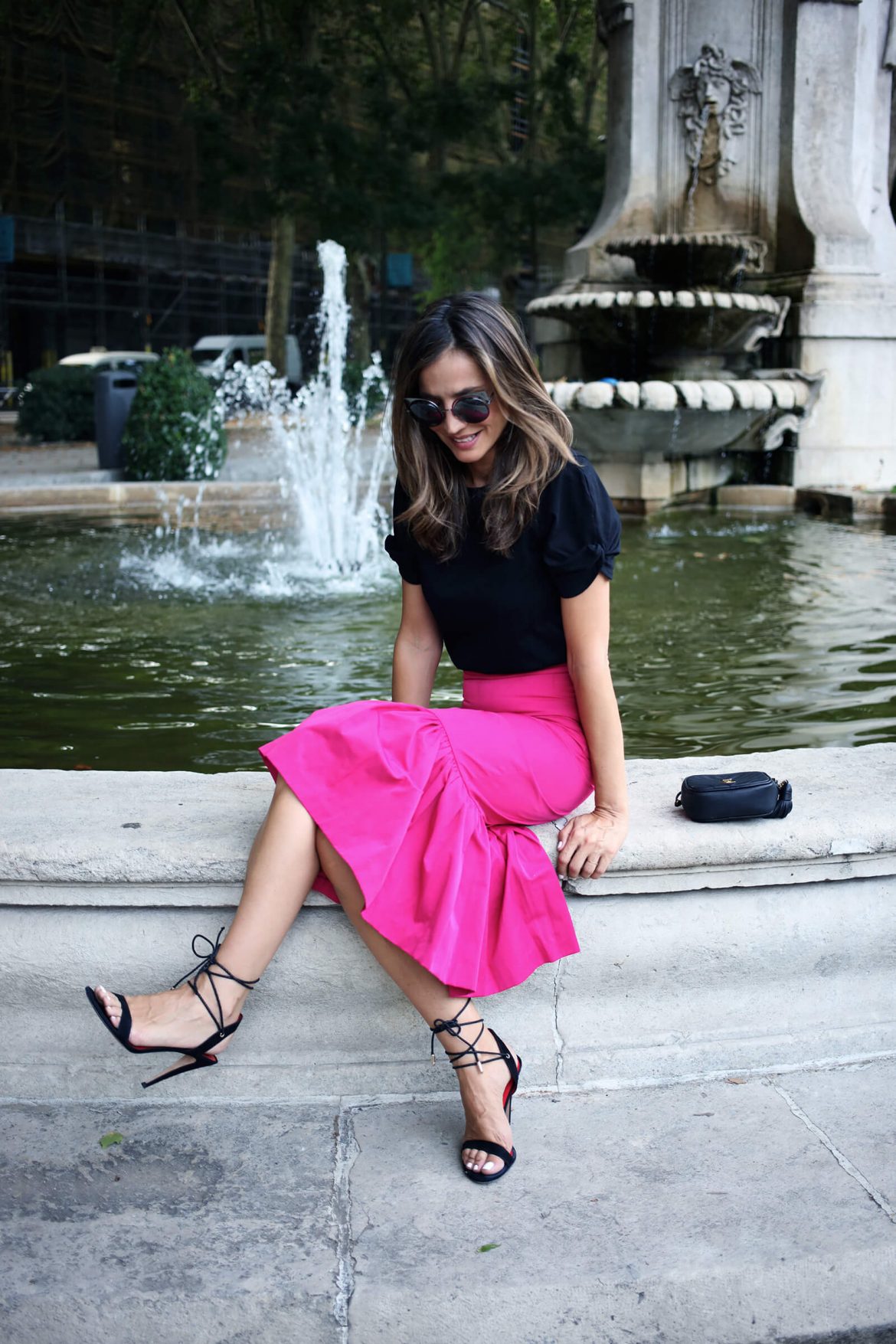 Sandalias negras pura lopez con cordones atados al tobillo, outfit verano combinado con falda de volantes fucsia